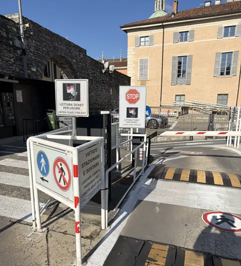 Wjazd na parking ze szlabanem, znakami i progami zwalniającymi