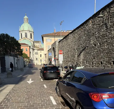 Droga dojazdowa do parkingu z widokiem na katedrę w Como i mury miejskie